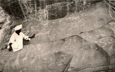 A member of the expedition examines Paleolithic rock carvings indicating the Sahara had once enjoyed a milder climate.